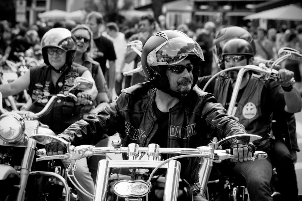 Black-and-white photo of bikers riding motorcycles at an outdoor event, exuding a cool vibe.