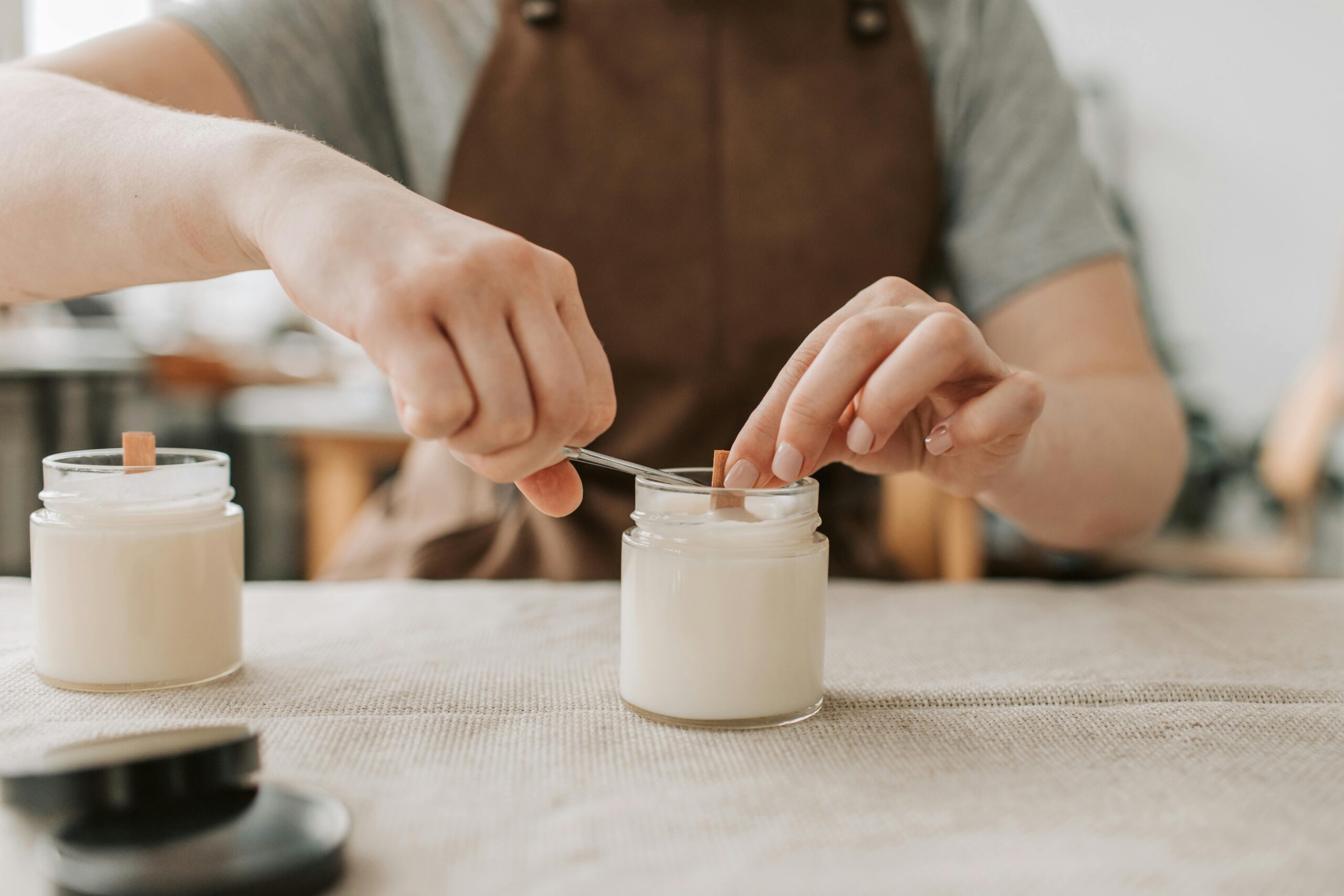 pexels-photo-6755809-6755809 Close-up of artisan crafting handmade candles with wooden wicks in workshop.