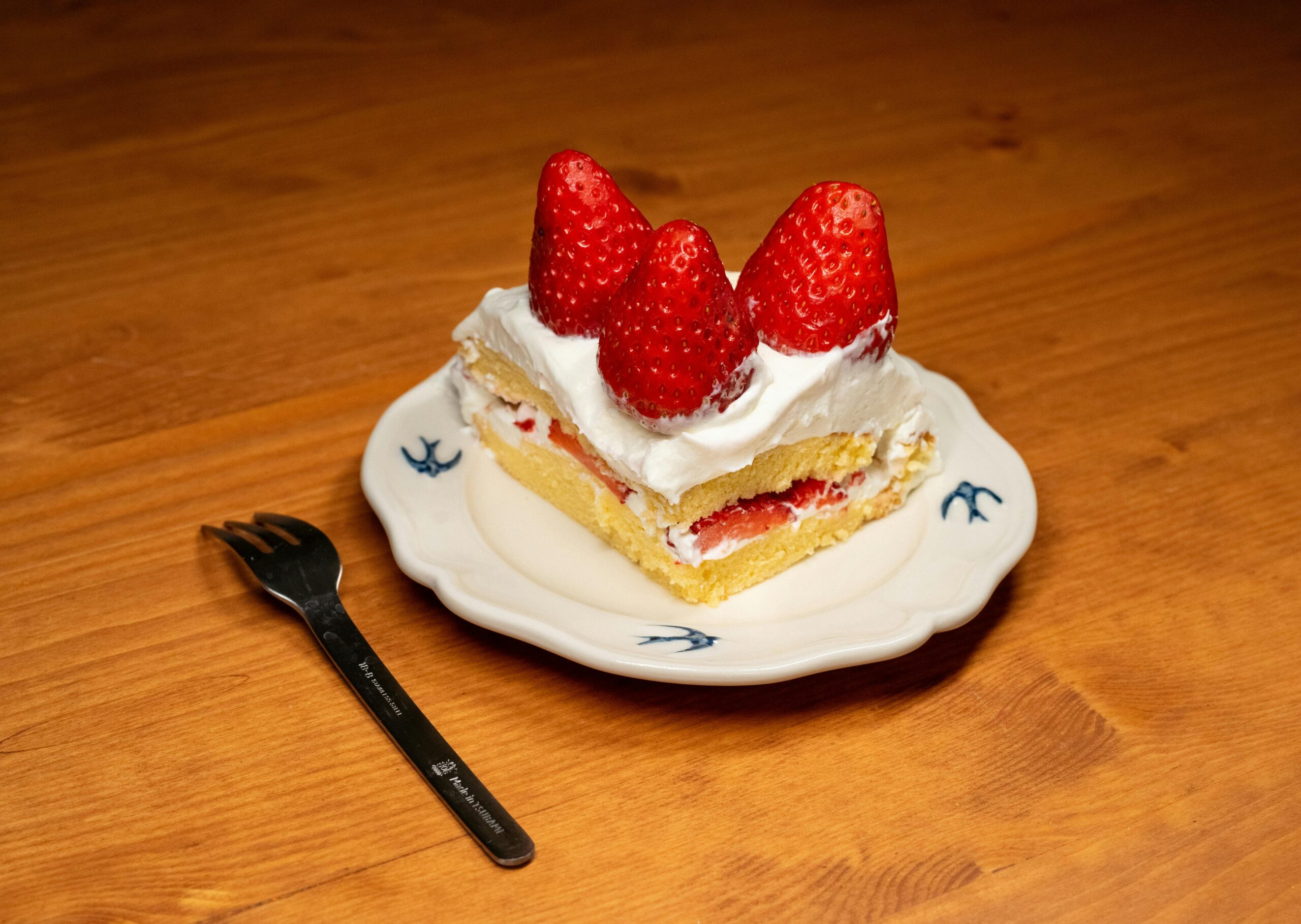 A tempting slice of strawberry shortcake topped with fresh strawberries on a decorative plate.