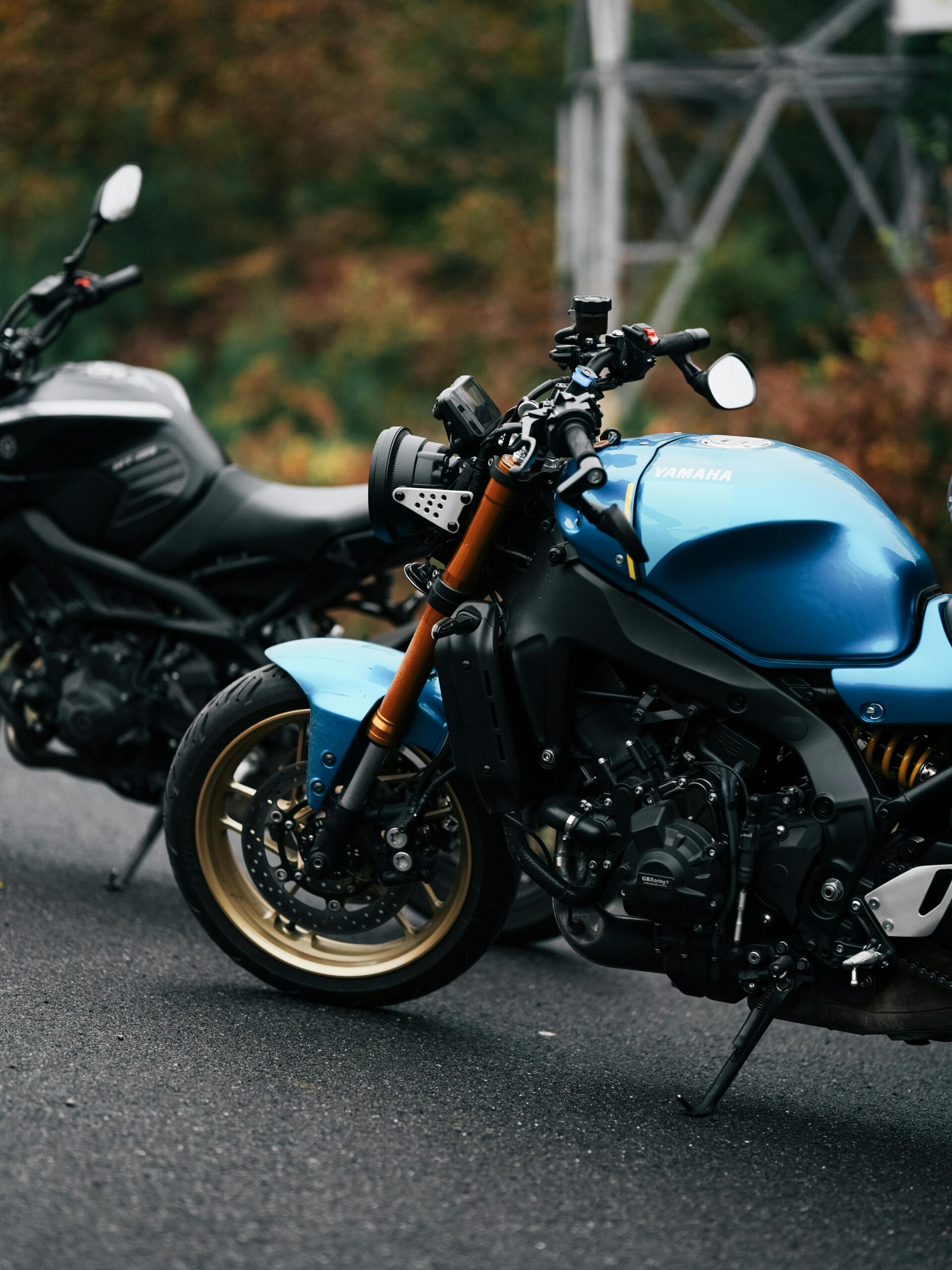 Close-up of two sport motorcycles parked on a paved road outdoors.